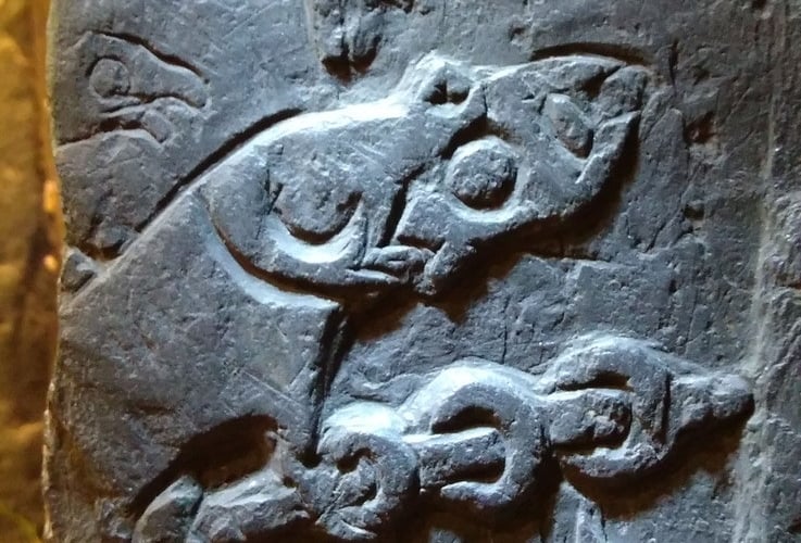 Detail from the fragment of cross showing Odin burning his fingers while roasting the dragon's heart