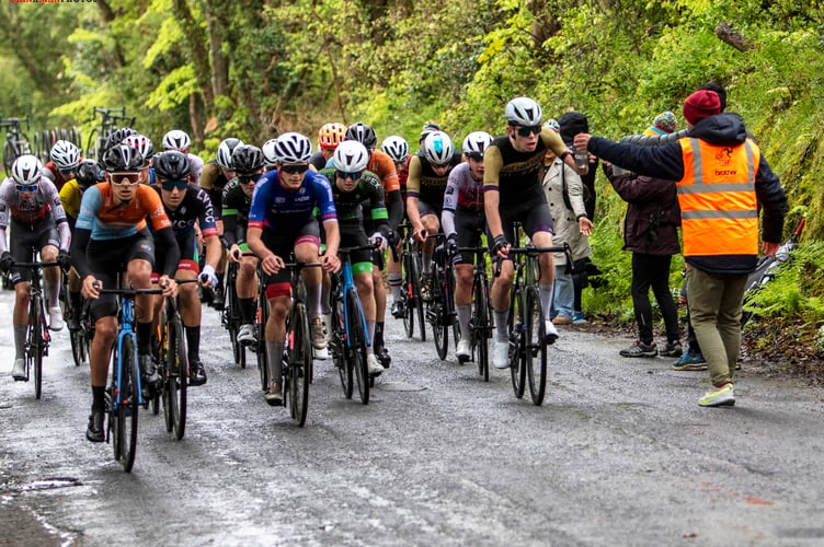 In soggy conditions, Utmost-Mezzo rider Ivan Sorby (far right) receives a bottle from his dad Rob in the feed zone during last weekend's Isle of Man Youth and Junior Cycling Tour. Ivan was second on the opening stage and 19th on stage two to finish third in the general classification (Photo: Gary Jones)