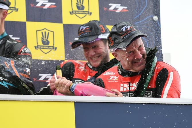 Dave Molyneux sprays the fizz on the podium with his godson Jake Roberts after finishing third in his final TT race last weekend (Photo: Dave Kneale)