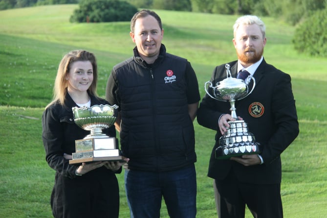 Brother and sister Robert and Emma Noon with their island golf championship trophies and Ollie Neale from competition sponsor Okell's 