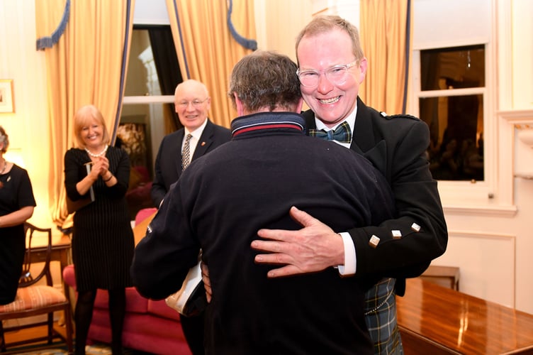 Milky Quayle BEM and John McGuiness MBE share a hug at Government House